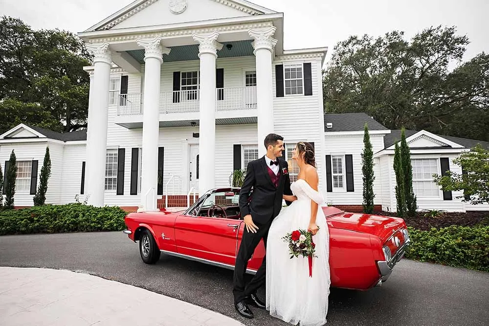 A couple with a red convertible at the estate house