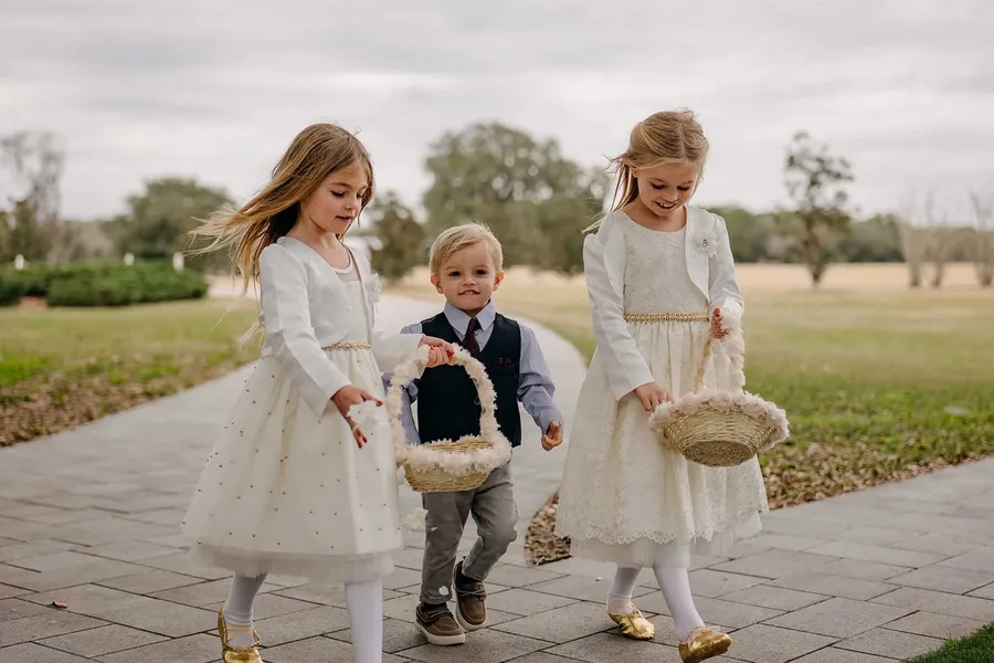 Two flower girls and a ring bearer walking the aisle