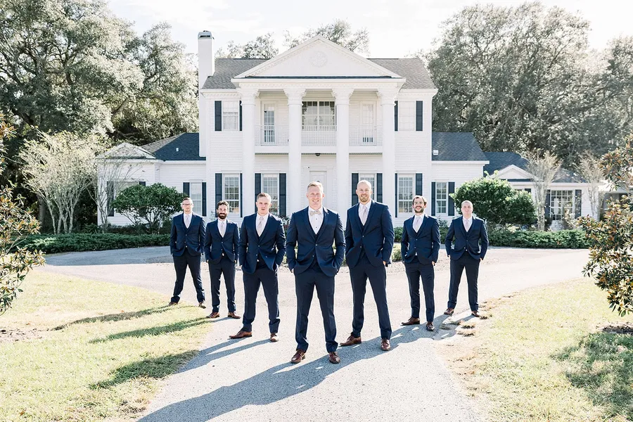 A groom and his groomsmen in front of the estate house