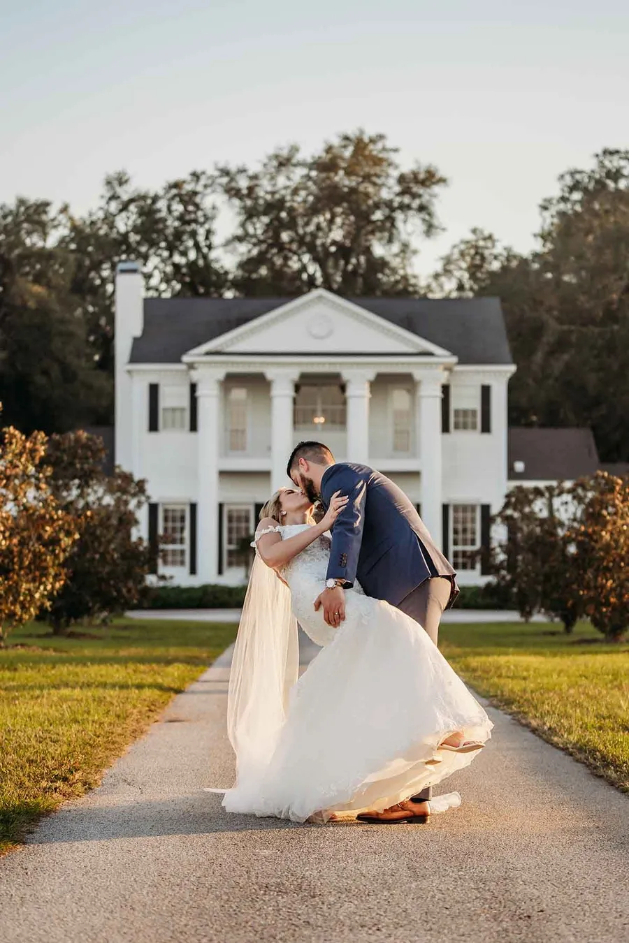 Savanah and Noah kissing on the drive in front of the estate house