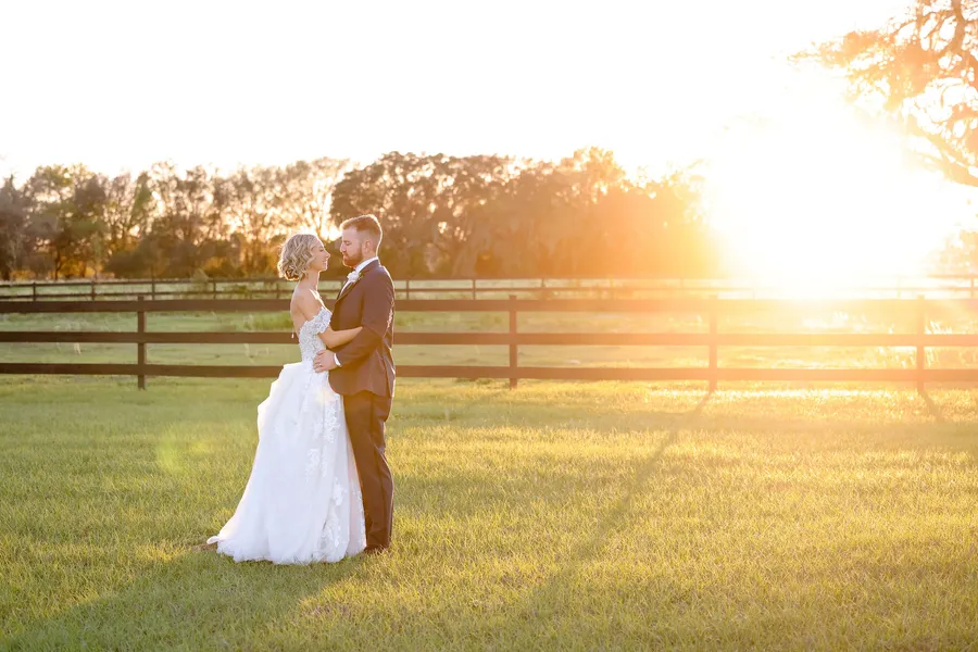A couple by the pasture fence at sunset